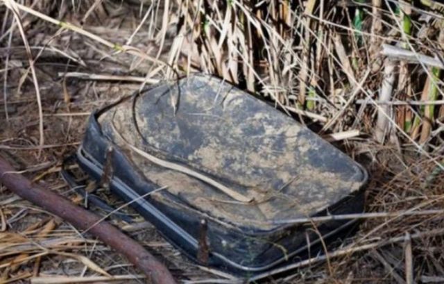 HT1. This woman came across an old, filthy luggage in a bush